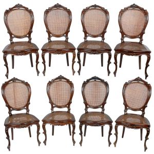 <b>Conjunto de 8 cadeiras</b> medalhão, em madeira entalhada, com encosto oval em palhinha e ornamentos florais no topo. Assento também em palhinha e pernas "cabriolet" com rocalhas. Alt. 108 cm