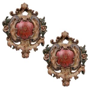 Belo <B>par de florões </B>barrocos policromados e entalhados com seus elementos característicos, apresentando dois botões de flores nas laterais e centro vermelho. Séc. XVIII. Med. 78 x 65 cm