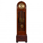 <b>Relógio carrilhão de coluna</b>, em madeira nobre, com mostrador circular em metal dourado finamente gravado. Pêndulo e pesos em metal trabalhado. Porta frontal envidraçada. Alt. 197 cm