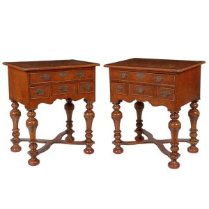 <b>Par de mesas de cabeceira </b>em nogueira, com tampo reto e frente guarnecida por quatro gavetas com ferragens. Saia recortada e pés torneados unidos por traves em "X". Med. 80 x 48 x 68 cm