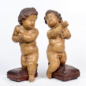 Belo <b>par de rechonchudos anjos </b>barrocos em madeira entalhada. As peças apoiam-se sobre o joelho em almofadas policromadas com cordão ao centro. Olhos em contas. Séc. XVIII. Alt. 52 cm
