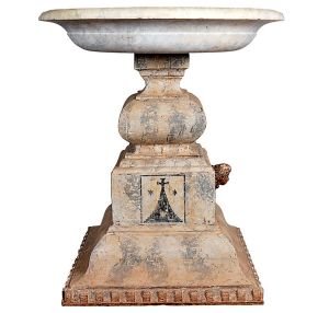 <b>Pia batismal </b>em mármore com cabeça de anjo projetada à frente e base em madeira original marmorizada com cercadura de elementos quadrangulares. Séc. XVIII. Alt. 100 cm; Diâm. 90 cm