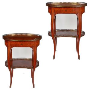 <b>Par de mesas de apoio </b>em madeira com "marqueterie". Tampo oval e prateleira inferior com grade vazada em metal dourado, apoiada sobre quatro pés recurvos. Med. 75 x 54 x 39 cm