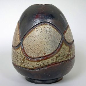 <b>Vaso </b>em cerâmica, com superfície esmaltada em tons terrosos e cinzentos, decorado com relevos geométricos em segmentos texturizados contrastantes. Marca "BG" na base. Alt. 30 cm