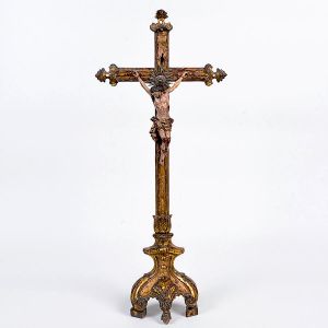 Belo <b>crucifixo </b>do séc. XVIII em madeira profusamente realçada a ouro. Ponteiras com entalhes em motivos barrocos e base com volutas. Resplendor em prata. Séc. XVIII. Alt. 67 cm