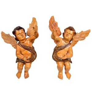 <b>Par de figuras de anjos de parede </b>esculpidos em madeira com pátina naturalística e planejamento movimentado de tonalidade ocre. Feições miradas ao céu. Séc. XVIII. Alt. 60 cm