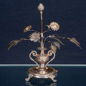 <b>Paliteiro </b>em prata cinzelada na forma de arranjo com flores e folhas, partindo de vaso bojudo com alças laterais. Base circular apoiada sobre quatro pés em voluta. Alt. 20 cm