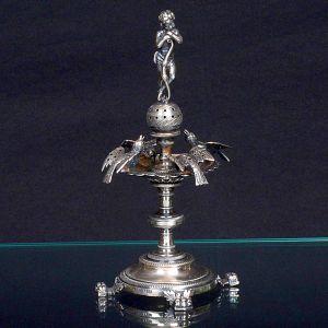 <b>Paliteiro </b>em prata portuguesa, moldada com figura de querubim central e quatro aves ao redor da taça superior. Pés de garra. Contrastes visíveis na base. Séc. XIX. Alt. 18 cm