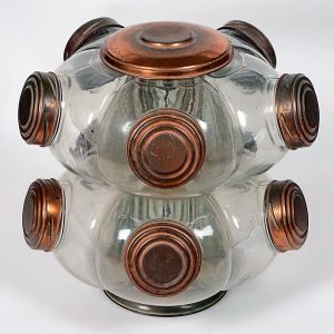 <b>Baleiro giratório </b>em vidro com tampas metálicas em tom acobreado. Composto por dois níveis com múltiplos compartimentos para armazenar guloseimas ou mantimentos. Alt. 50 cm