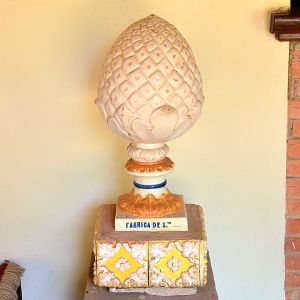 <b>Pinha </b>em cerâmica esmaltada em tons de bege e detalhes alaranjados, sobre pedestal quadrado, executada pela Fábrica de Santo António do Porto, com base marcada. Alt. 70 cm