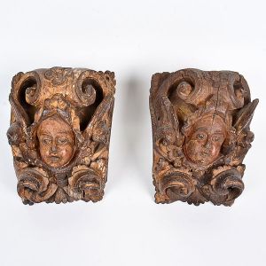 Lindo <b>par de talhas </b>barrocas em madeira de concepção barroca apresentando à frente cabeças de anjos cercados por volutas. Resquícios de policromia. Séc. XVIII. Alt. 24 cm