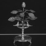 <b>Paliteiro </b>em prata brasileira apresentando chafariz com pássaros encimado por folhagens e flor. Base circular com friso lavrado, apoiado em pés estilizados. Alt. 20 cm