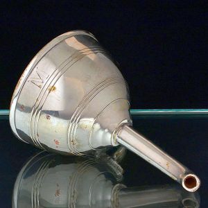 <b>Funil </b>em prata inglesa decorada com folhas de parreira e cacho de uvas. Corpo cônico liso, com longo bico vertedor. Apresenta gravação com a letra "M". Alt. 12,5 cm
