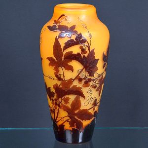 <b>Gallé</b> - Vaso em vidro camafeu com fundo âmbar e sobreposição em tom castanho, decorado em alto-relevo com folhas e ramos de videira. Assinado na lateral. Alt. 38 cm