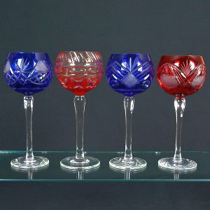 <b>Conjunto de taças </b>em cristal colorido "overlay", com 9 peças na cor azul cobalto e 7 na cor rubi, todas com bojo ricamente lapidado e haste lisa. Alt. 25 cm