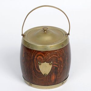 <b>Balde de gelo </b>em madeira com montagens em metal prateado, EPNS, no formato de barril com tampa e alça móvel. Apresenta escudo frontal decorativo. Alt. 14 cm