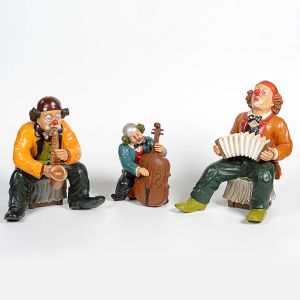 <b>Conjunto de 3 palhaços músicos</b>, em resina pintada, em diferentes poses: um tocando saxofone, outro contrabaixo e o terceiro acordeom. Alt. 35, 25 e 36 cm