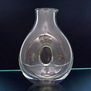 <b>Decanter </b>em cristal, de corpo bojudo, com recorte vazado central emoldurado pelo próprio vidro, formando detalhe ovalado. Bico levemente assimétrico.