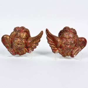 Lindo <B>par de pequenas cabeças de anjos </B>no estilo barroco em monobloco de madeira com policromia vermelha sob douração de época. Séc. XIX. Alt. 12 cm
