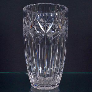 <b>Vaso </b>em cristal, de corpo cilíndrico, com lapidações em forma de estrelas na parte superior e cortes verticais alongados na base. Alt. 26 cm