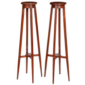 <b>Par de colunas de pés altos </b>em madeira. Estrutura alta, com tampo circular e quatro pés unidos por cruzeta inferior. Alt. 117 cm