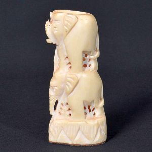 <b>Estatueta em marfim</b>, representando elefantes empilhados, com detalhes vazados e base geométrica. Acompanha espetos. Alt. 11 cm