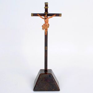 <b>Cristo </b>crucificado, em cruz madeira escura, com terminações metálicas e resplendor central. Base piramidal. Alt. 45 cm