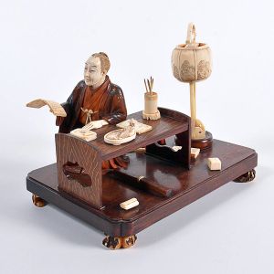 <b>Grupo escultórico </b>em marfim e madeira, representando escriba oriental em mesa de trabalho com utensílios. Med. 23 x 14 cm