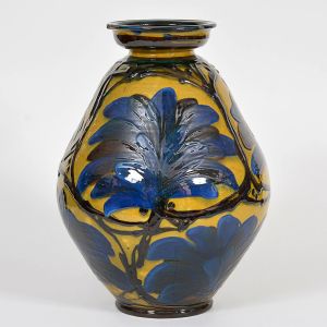 <b>Vaso </b>em cerâmica vidrada, com bojo abaulado e decoração em relevo de grandes folhas azuladas sobre fundo ocre. Alt. 37 cm