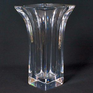 <b>Vaso </b>em cristal incolor, com corpo facetado de linhas verticais e base quadrada, abrindo em boca alargada. Alt. 24,5 cm