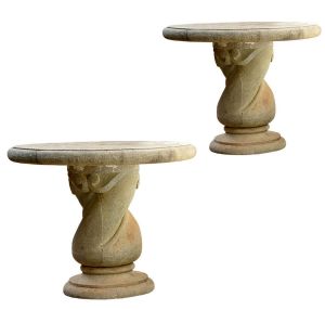 <b>Par de mesas </b>em pedra lavrada, com tampos circulares espessos apoiados sobre bases esculpidas retorcidas com volutas.