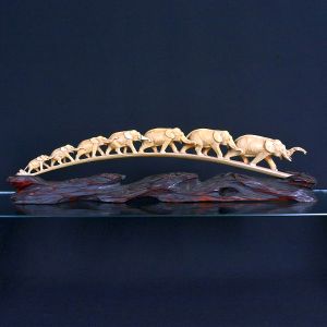 <b>Escultura chinesa </b>em marfim representando série de sete elefantes em fila. Base em madeira. Compr. 65 cm