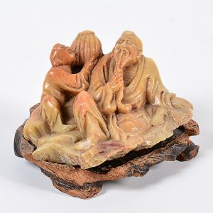 <b>Escultura em pedra</b>, representando figuras orientais reclinadas, acompanhada de base em madeira. Alt. 10 cm