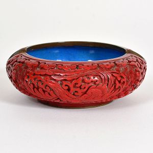 <b>Cinzeiro </b>em "cinnabar" entalhado com motivos orientais e interior em esmalte azul. Diâm. 10,5 cm