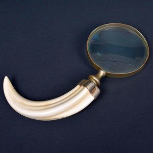 <b>Lupa com cabo </b>em forma de presa, com estrutura metálica dourada. Compr. 24 cm