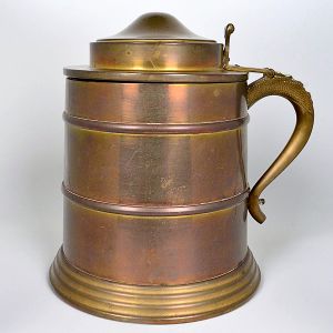 "<b>Tankard</b>" em metal, com tampa articulada e alça decorada em relevo. Alt. 30 cm
