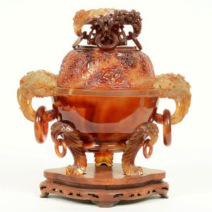 Elaborado <B>incensário chinês </B>em ágata vermelha. Apresenta bojo globular com tampa vazada em arabescos e encimada por receptáculo com quatro elementos anelados pendentes. Duplas alças com belos entalhes e outros anelados. A peça está assentada em triplos pés recurvados e estilizados. A ágata vermelha é um tipo microcristalino de quartzo, valorizada na China antiga como uma das pedras preciosas mais estimadas, também conhecida com "Nan Hong Yu". Alt. 9 cm; Compr. 32 cm