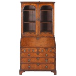 "<B>Bureau bookcase</B>" inglês, do período vitoriano. Parte superior em armário de portas envidraçadas com duas prateleiras e pequenas gavetas e duas pranchetas deslizantes para apoio de castiçais. O escritório com tampo reclinável forrado com couro, apresenta seis gavetinhas ladeando o par de nichos com cofre central. Parte inferior com par de gavetas sobre três gavetões. Ferragens da época. Med. fechada 193 x 87 x 54 cm; Med. aberta 193 x 87 x 85 cm