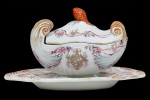 <b>Terrina para molho com seu "presentoir"</b>, em porcelana Companhia das Índias brasonada, sendo a terrina em forma de "coquille", decorada com guirlandas floridas e estilizações nos esmaltes da Família Rosa com realces a ouro. Pega modelada em pinha em "rouge de fer". "Presentoir" acompanhando os mesmos motivos decorativos. Séc. XVIII. O "presentoir" encontra-se com craquelê na frente e verso. Med. do "presentoir" 22 x 18 cm; Compr. da terrina 15 cm