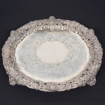Extraordinária e <B>grande salva </B>em prata inglesa de forma circular, repuxada e cinzelada. Fundo com flores, volutas, reservas com escamados e texturizados. Centro liso. Borda em requintado trabalho de repuxados e cinzelados com máscaras bacantes e composições com flores, cachos de uvas e folhas de parreira. Os quatro pés seguem o mesmo estilo. Contraste da cidade de Londres de 1847 e marca ilegível de prateiro. Diâm. 64 cm. Peso 6295 gramas.