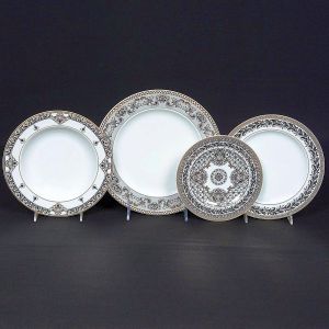 Refinado <b>serviço de 18 pratos </b>em porcelana Rosenthal com a sofisticada decoração Marqueterie, para Versace, inspirada em padrões clássicos de marchetaria, decorada em rico trabalho ornamental em preto e platina, formando desenhos geométricos e arabescos que se destacam sobre o fundo branco da porcelana Composto por 6 pratos rasos, 6 pratos fundos e 6 pratos de sobremesa. Assinatura Versace e a icônica Medusa no selo posterior.