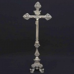 Magnífico <b>crucifixo </b>em prata brasileira do séc. XIX. Cruz em caneluras com três ponteiras lindamente trabalhadas em "rocailles" barrocos. Haste movimentada decorada com folhas de acanto sobre base trípode de aba gomada e decoração em harmonia ao conjunto. Contraste 10 Dinheiros e marca do ourives dso Rio de Janeiro Domingos Farini, citado entre 1848 e 1883, conhecida com marcas do toque BR-156.0 e BR-162.0. Alt. 89 cm