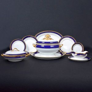<b>Serviço de jantar </b>em porcelana portuguesa Vista Alegre, com fundo branco e bordas decoradas em azul cobalto e ouro. Marca da manufatura no verso. Constando de 19 pratos rasos, 12 pratos fundos, 9 pratos de sobremesa, 11 pratos de pão, 1 terrina c/ "presentoir", 1 legumeira c/ tampa, 5 travessas de vários tamanhos e 1 molheira. Total de 59 peças. Med. da travessa maior 38 cm; Med. da travessa menor 27 cm