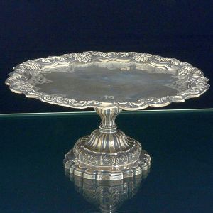 Raríssima <b>esmoleira </b>em prata portuguesa de época e estilo D. João V. Centro liso com borda e base lavradas e repuxadas e cinzeladas com os elementos característicos da época em composições de acantos, volutas e elementos concheados. Contraste da cidade de Lisboa usado de 1721 a 1750 e marca do ourives DG, reg. nº 2446 no livro de Vidal. Peça de coleção. Alt. 14,5 cm; Diâm. 31 cm. Peso 1075 gramas.