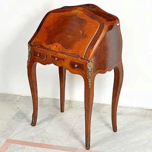 "<b>Bonheur du jour</b>" francesa construída em diversos cortes de nogueira, apresentando forma levemente "bombée" e linhas movimentadas. Tampo reclinável com interior apresentando nicho central com seis pequenas gavetas. Outras três gavetinhas externas. Pernas longilíneas sendo as anteriores decoradas com ferragens de bronze. Séc. XIX. Med. fechada 96,5 x 61 x 40 cm; Med. aberta 96,5 x 61 x 73 cm 