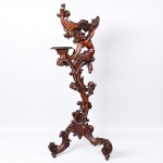 Belíssima e exótica <b>coluna italiana</b>, do séc. XVIII, construída em carvalho. Apresenta três grandes volutas minuciosamente esculpidas, tendo a intermediária figura feminina de feições infantis. Dorso parcialmente desnudo com pano amarrado na altura do sexo. A figura sustenta uma navete que se apoia em segmento ondulado terminado em pequeno "plateau". Triplos pés enrolados. Alt. 135 cm