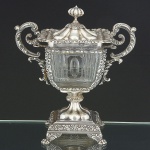 Belíssimo <b>porta caviar </b>em cristal Baccarat lapidado com montagem em prata francesa profusamente decorada com diversas composições vegetalistas. Alças em curvas e contracurvas, pega da tampa modelada em pinha e pés em garras. Apresenta 11 porta colheres, faltando um deles. Contraste "Cabeça de Minerva" e marca de prateiro. Séc. XIX. Alt. 28 cm; Larg. sem as alças 24,5 cm