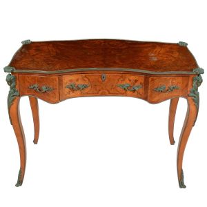 "<b>Bureau</b>" francês no estilo Louis XV construído em madeira clara europeia. Tampo retangular recortado com três gavetas anteriores movimentadas. Bela "marqueterie" em composição de flores e folhagens. Pernas recurvadas. Puxadores e ferragens protetoras em bronze sendo os cantos decorados com acantos e ilhargas com cabeças de cabrito montês sobre volutas. Séc. XVIII.