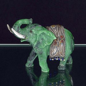 <b>LUIZ FERREIRA</b> - Escultura em jade representando elefante oriental. Presas e manto montado em prata. Aplicações em "cabochons". O elefante traz o simbolismo de boa sorte, sabedoria, persistência e determinação e apresenta forte relação com o budismo e hinduísmo. Contraste da prata da cidade do Porto, 833 ml e punção do referido ourives. Alt. 10.5 cm; Compr. 14,5 cm