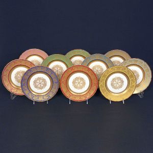 Elegante <b>conjunto de jantar composto por 12 pratos rasos</b>, em porcelana Ivory da prestigiada manufatura alemã Rosenthal. Apresenta rica decoração em bordadura larga, com arabescos e motivos clássicos em dourado, aplicados sobre paleta variada em tons vibrantes  incluindo azul, verde, vermelho, rosa e amarelo e medalhão floral estilizado ao centro. Marcas no verso.